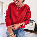 Light weight red ribbed long sleeved top with white whip stitching at the round neck and cuffs.