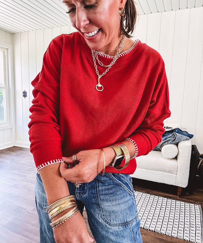 Light weight red ribbed long sleeved top with white whip stitching at the round neck and cuffs.
