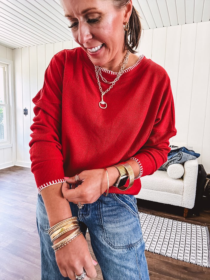 Light weight red ribbed long sleeved top with white whip stitching at the round neck and cuffs.