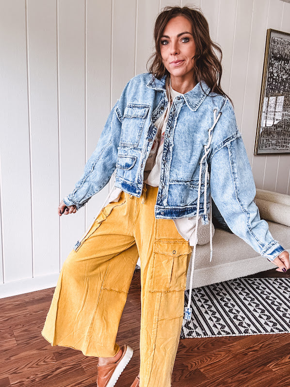 Light wash denim jacket with rope and grommet detail on the front.