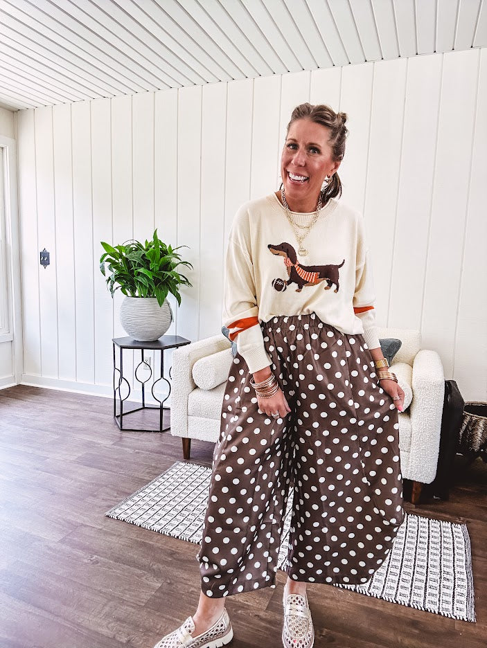 Cream lightweight long sleeved sweater with Weiner Dog graphic on front with orange stripes at the sleeves.