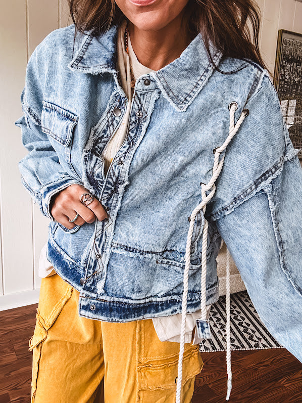 Light wash denim jacket with rope and grommet detail on the front.