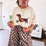 Cream lightweight long sleeved sweater with Weiner Dog graphic on front with orange stripes at the sleeves.