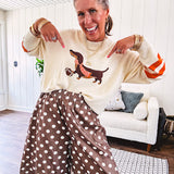 Cream lightweight long sleeved sweater with Weiner Dog graphic on front with orange stripes at the sleeves.
