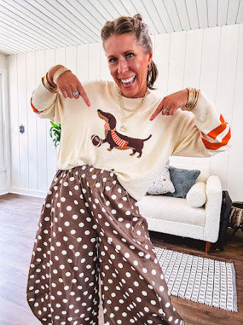 Cream lightweight long sleeved sweater with Weiner Dog graphic on front with orange stripes at the sleeves.