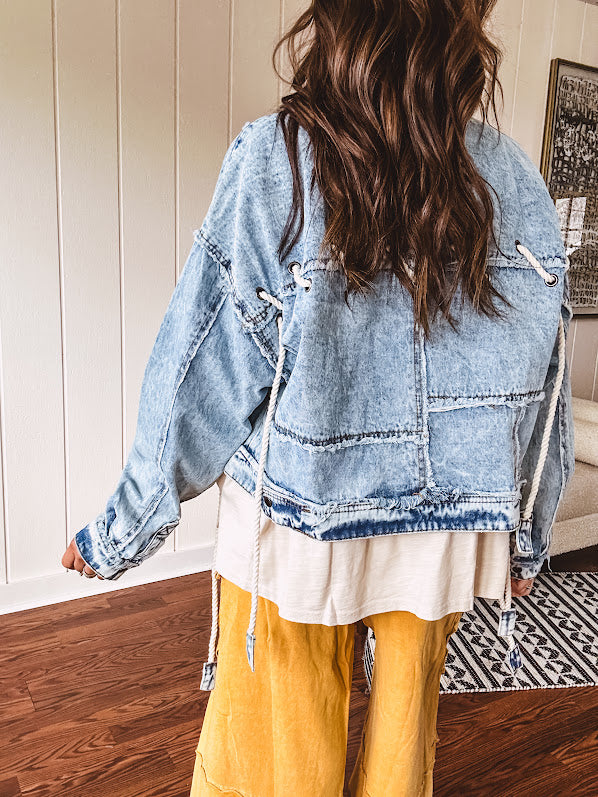 Light wash denim jacket with rope and grommet detail on the front.