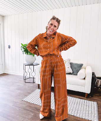 Wide leg rust pants with elastic waist and front pleats with geometric white stitching print throughout.