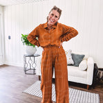 Wide leg rust pants with elastic waist and front pleats with geometric white stitching print throughout.