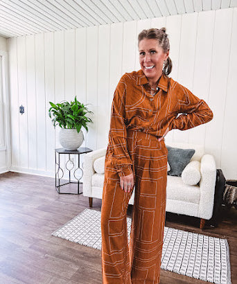 Wide leg rust pants with elastic waist and front pleats with geometric white stitching print throughout.