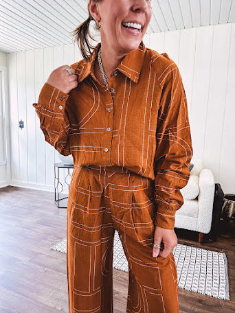 Lightweight rust button front long sleeved shirt with collar and white geometric stitching print throughout.