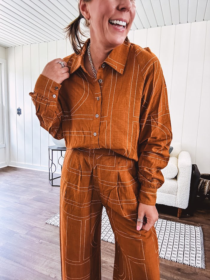 Lightweight rust button front long sleeved shirt with collar and white geometric stitching print throughout.