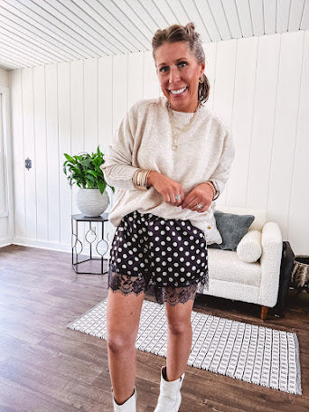 Black satin shorts with white polka dots, elastic waist and lace trim at the hems.