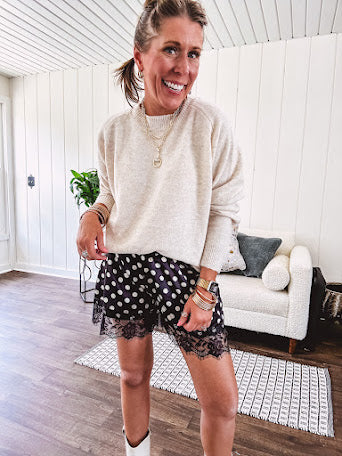 Black satin shorts with white polka dots, elastic waist and lace trim at the hems.