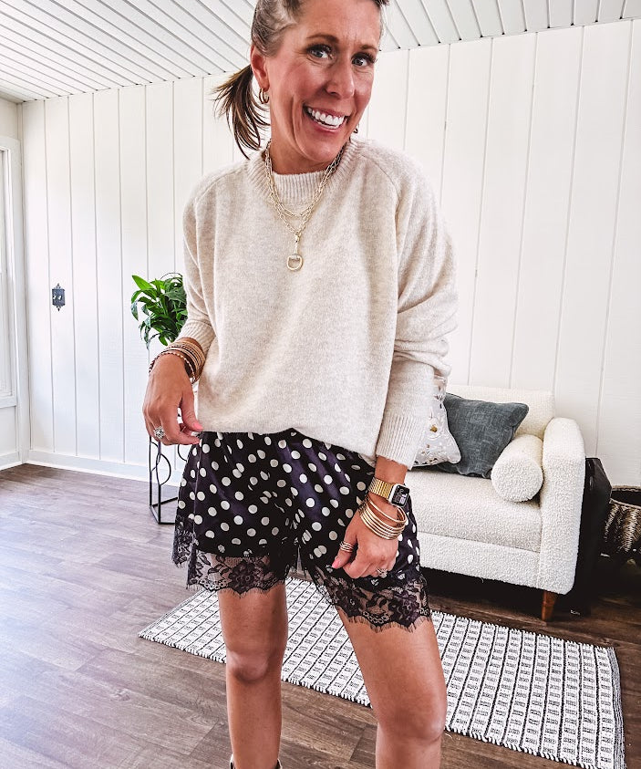 Black satin shorts with white polka dots, elastic waist and lace trim at the hems.