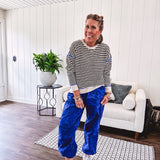 Lightweight black and cream striped crewneck sweater with royal blue contrast stripes at the shoulders, cuffs and hem.