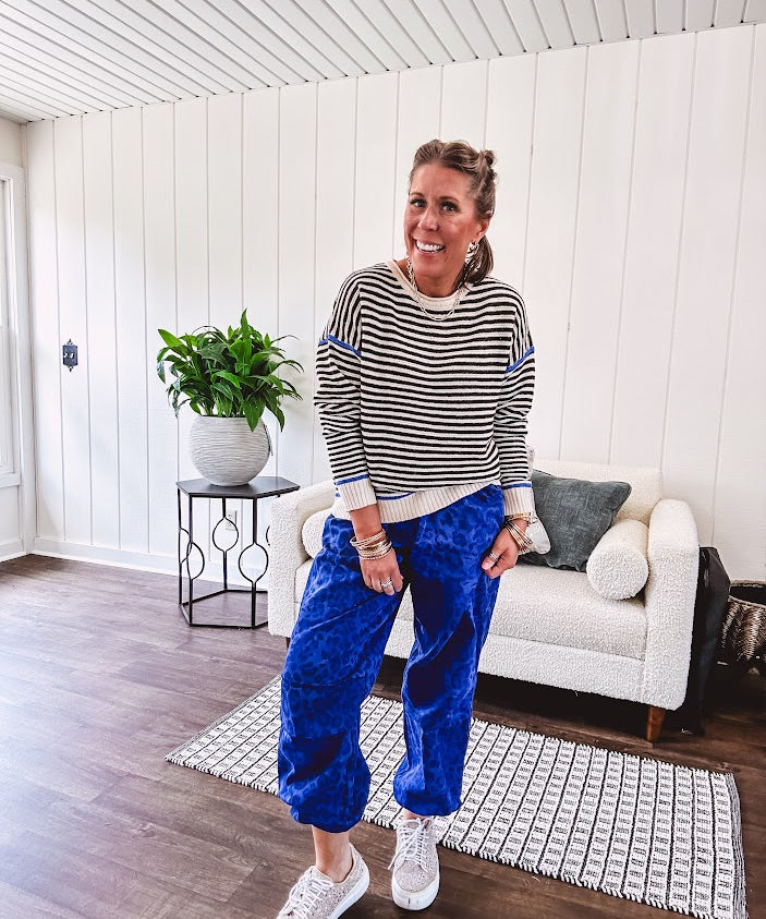 Lightweight black and cream striped crewneck sweater with royal blue contrast stripes at the shoulders, cuffs and hem.