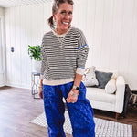 Lightweight black and cream striped crewneck sweater with royal blue contrast stripes at the shoulders, cuffs and hem.