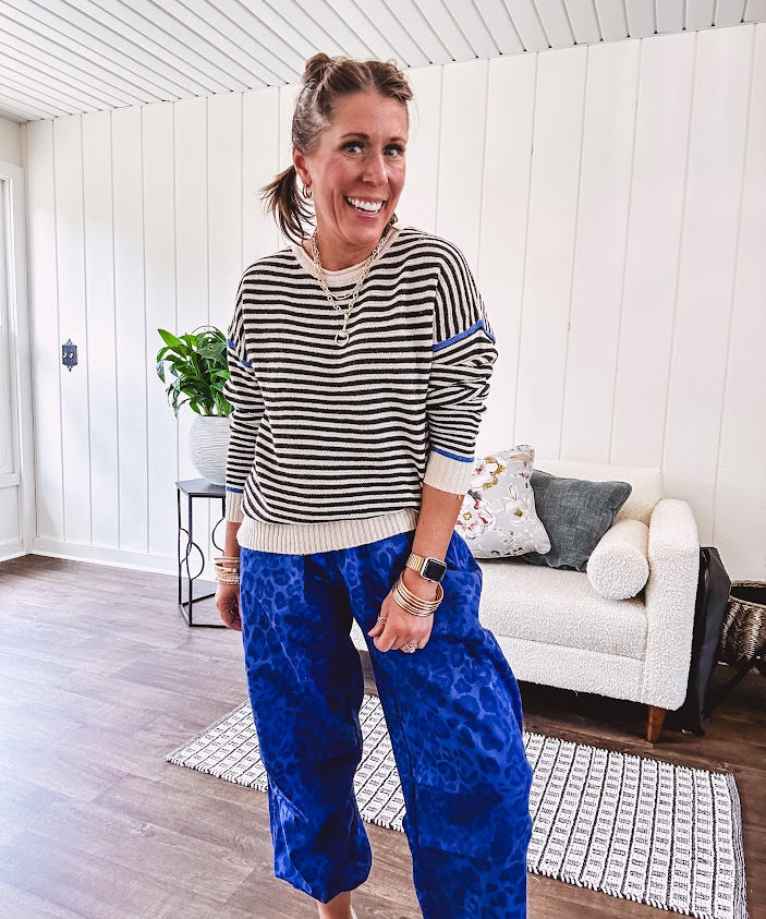 Lightweight black and cream striped crewneck sweater with royal blue contrast stripes at the shoulders, cuffs and hem.