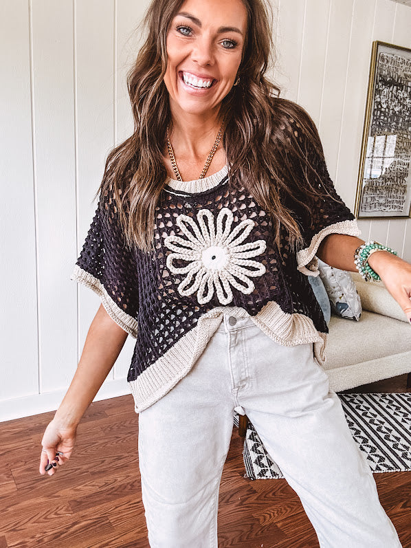 Open weave crochet sweater with 3/4 sleeves and large contrasting crochet flower on the front and contrasting trim. Oversized. Available in multiple colors.