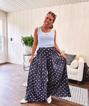 Thin, lightweight ultra wide leg pants in dark denim shade with light blue polka dots throughout and elastic waist with ruffles on the waist and front pockets.