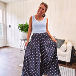 Thin, lightweight ultra wide leg pants in dark denim shade with light blue polka dots throughout and elastic waist with ruffles on the waist and front pockets.
