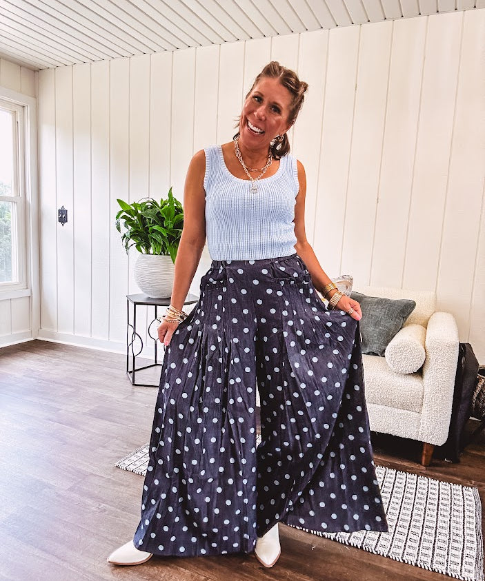 Thin, lightweight ultra wide leg pants in dark denim shade with light blue polka dots throughout and elastic waist with ruffles on the waist and front pockets.