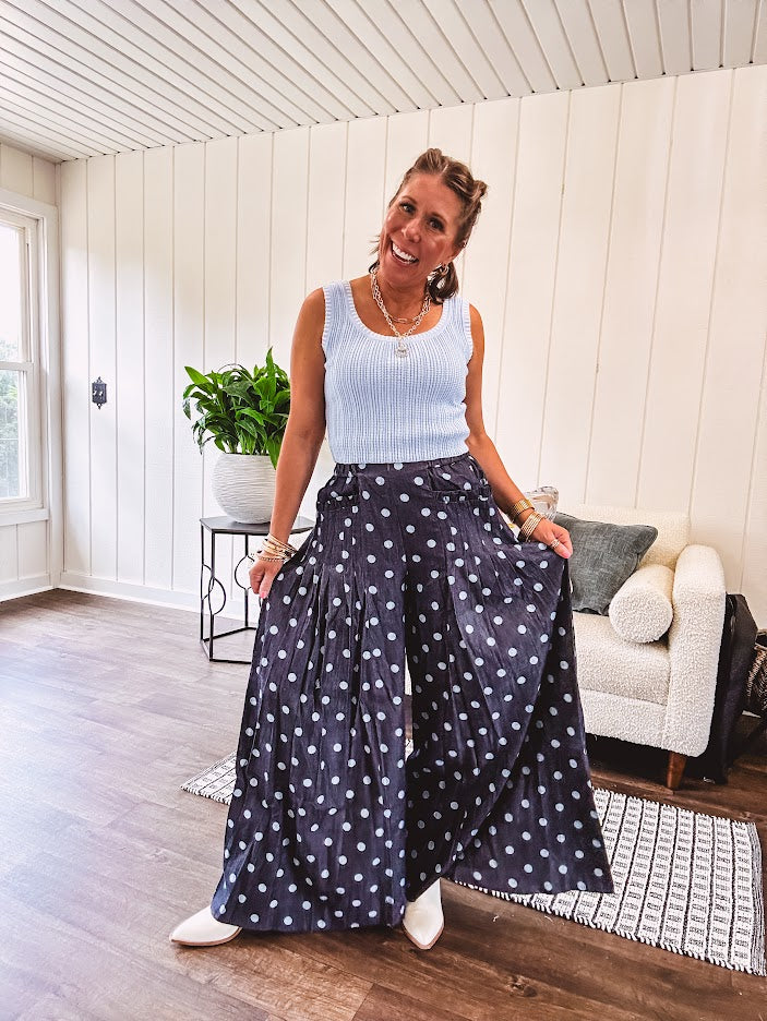 Thin, lightweight ultra wide leg pants in dark denim shade with light blue polka dots throughout and elastic waist with ruffles on the waist and front pockets.