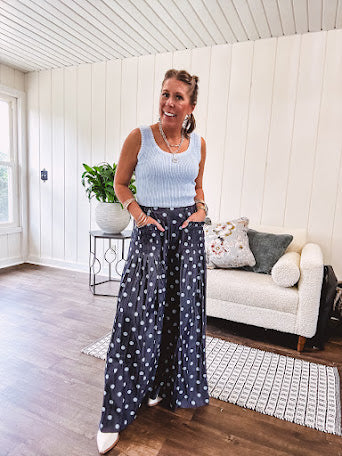 Thin, lightweight ultra wide leg pants in dark denim shade with light blue polka dots throughout and elastic waist with ruffles on the waist and front pockets.