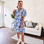 Thin, lightweight mini dress with white flowers lined in black on a royal blue background, mock ruffled collar, V neck and puffed sleeves with pockets.
