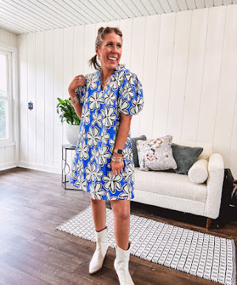 Thin, lightweight mini dress with white flowers lined in black on a royal blue background, mock ruffled collar, V neck and puffed sleeves with pockets.