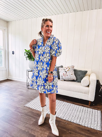 Thin, lightweight mini dress with white flowers lined in black on a royal blue background, mock ruffled collar, V neck and puffed sleeves with pockets.