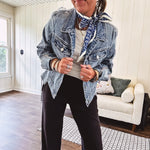 Medium wash non-stretch denim jacket with classic trim, raw, uneven hem and cuffs with silver hardware and cropped length.