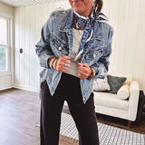 Medium wash non-stretch denim jacket with classic trim, raw, uneven hem and cuffs with silver hardware and cropped length.