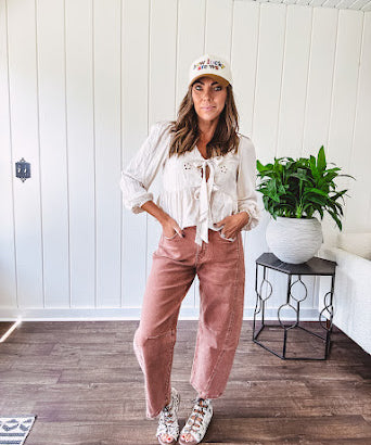 Lightweight long sleeved top in light khaki with two front bow ties at the deep scalloped V neck, eyelet embroidered flowers on the front and ruffled hem at the waist.