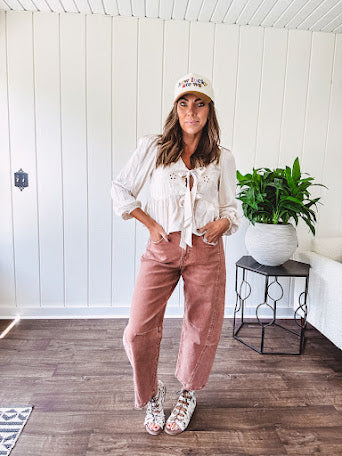 Lightweight long sleeved top in light khaki with two front bow ties at the deep scalloped V neck, eyelet embroidered flowers on the front and ruffled hem at the waist.