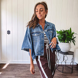 Medium wash denim cape jacket with seam detail, collar and silver buttons down the front and on the front pockets.