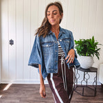 Medium wash denim cape jacket with seam detail, collar and silver buttons down the front and on the front pockets.