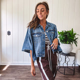 Medium wash denim cape jacket with seam detail, collar and silver buttons down the front and on the front pockets.