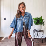 Medium wash denim cape jacket with seam detail, collar and silver buttons down the front and on the front pockets.