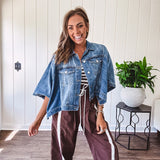 Medium wash denim cape jacket with seam detail, collar and silver buttons down the front and on the front pockets.
