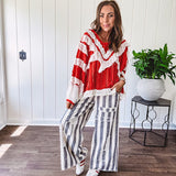 Apple red ruffle texture boho style long sleeved top with round neck and cream eyelet lace detail in a V shape across the front and on the sleeves and hem.