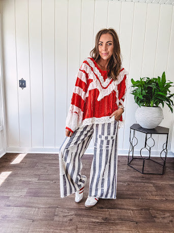 Apple red ruffle texture boho style long sleeved top with round neck and cream eyelet lace detail in a V shape across the front and on the sleeves and hem.