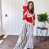 Apple red ruffle texture boho style long sleeved top with round neck and cream eyelet lace detail in a V shape across the front and on the sleeves and hem.