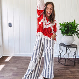 Apple red ruffle texture boho style long sleeved top with round neck and cream eyelet lace detail in a V shape across the front and on the sleeves and hem.