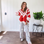 Apple red ruffle texture boho style long sleeved top with round neck and cream eyelet lace detail in a V shape across the front and on the sleeves and hem.