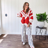 Apple red ruffle texture boho style long sleeved top with round neck and cream eyelet lace detail in a V shape across the front and on the sleeves and hem.