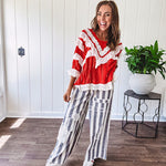 Apple red ruffle texture boho style long sleeved top with round neck and cream eyelet lace detail in a V shape across the front and on the sleeves and hem.