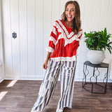 Apple red ruffle texture boho style long sleeved top with round neck and cream eyelet lace detail in a V shape across the front and on the sleeves and hem.