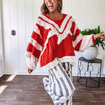 Apple red ruffle texture boho style long sleeved top with round neck and cream eyelet lace detail in a V shape across the front and on the sleeves and hem.