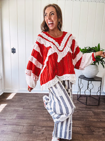Apple red ruffle texture boho style long sleeved top with round neck and cream eyelet lace detail in a V shape across the front and on the sleeves and hem.